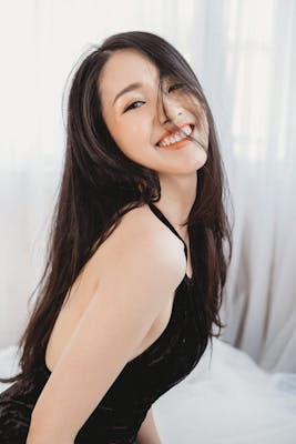 Cheerful woman in a black dress smiling brightly in an indoor setting.