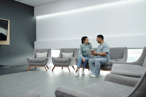 Doctor and patient discussing health in a modern waiting room with digital tablet.