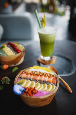 Vibrant acai bowl with fruits and a refreshing green juice on a wooden table.