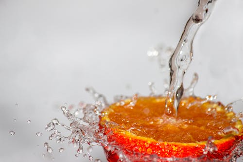 A high-speed capture of water splashing onto a juicy orange slice, creating a refreshing visual.