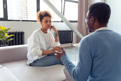 Two individuals engaged in a thoughtful therapy session indoors.